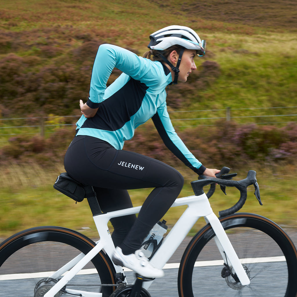 Cyclist wearing blue 3L Core Rain Jacket riding white bike in autumn outdoors