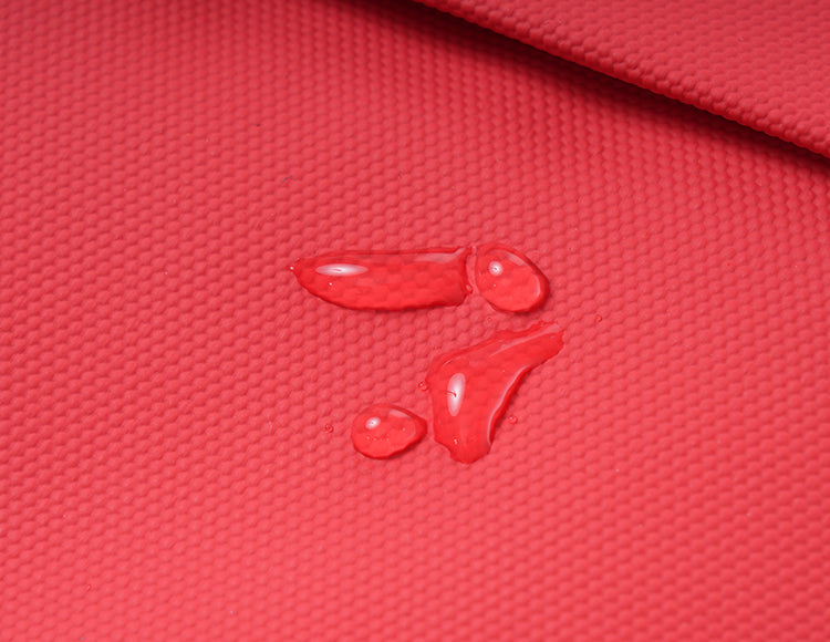 Water-resistant red textured fabric of handlebar bag with water droplets on surface