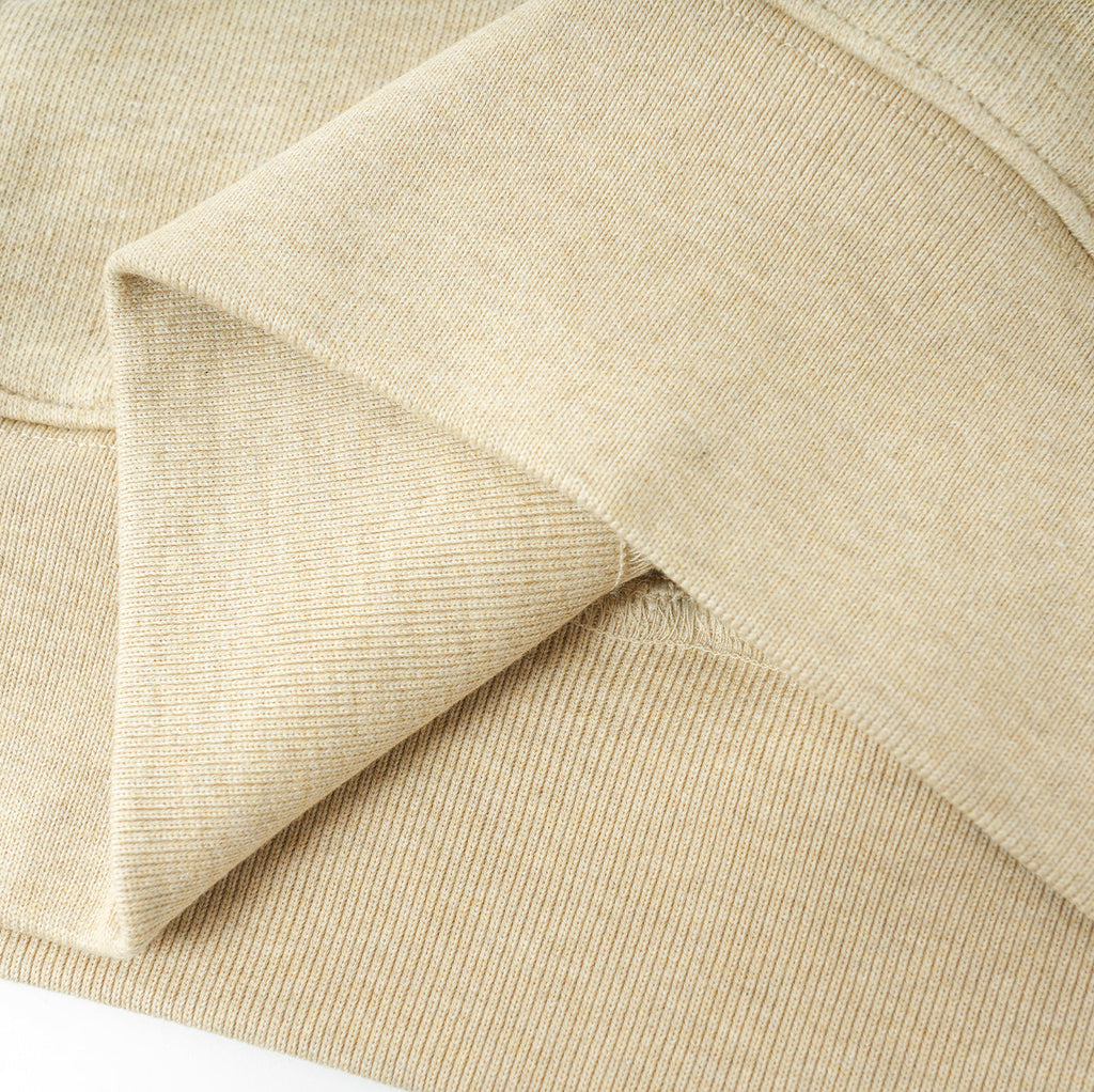 Close-up of beige Essentials Cotton Crewneck sweatshirt fabric showing soft, ribbed texture and relaxed fit design for comfort and movement.