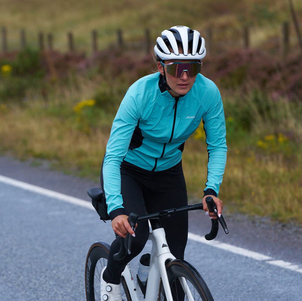 Cyclist wearing 3L Core Rain Jacket in blue riding on road in autumn weather