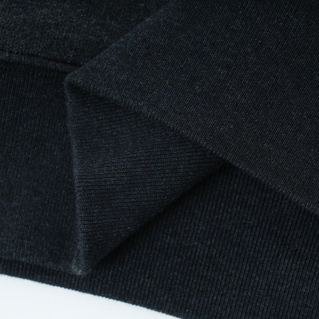 Close-up of black Essentials Cotton Crewneck sweatshirt fabric with ribbed cuffs and hem