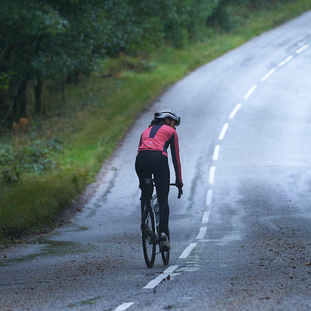 Cyclist wearing 3L Core Rain Jacket riding on wet road in autumn setting